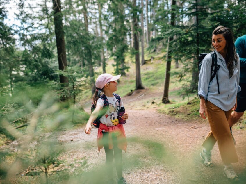 Familie beim Wandern durch den Wald in Hafling in Südtirol